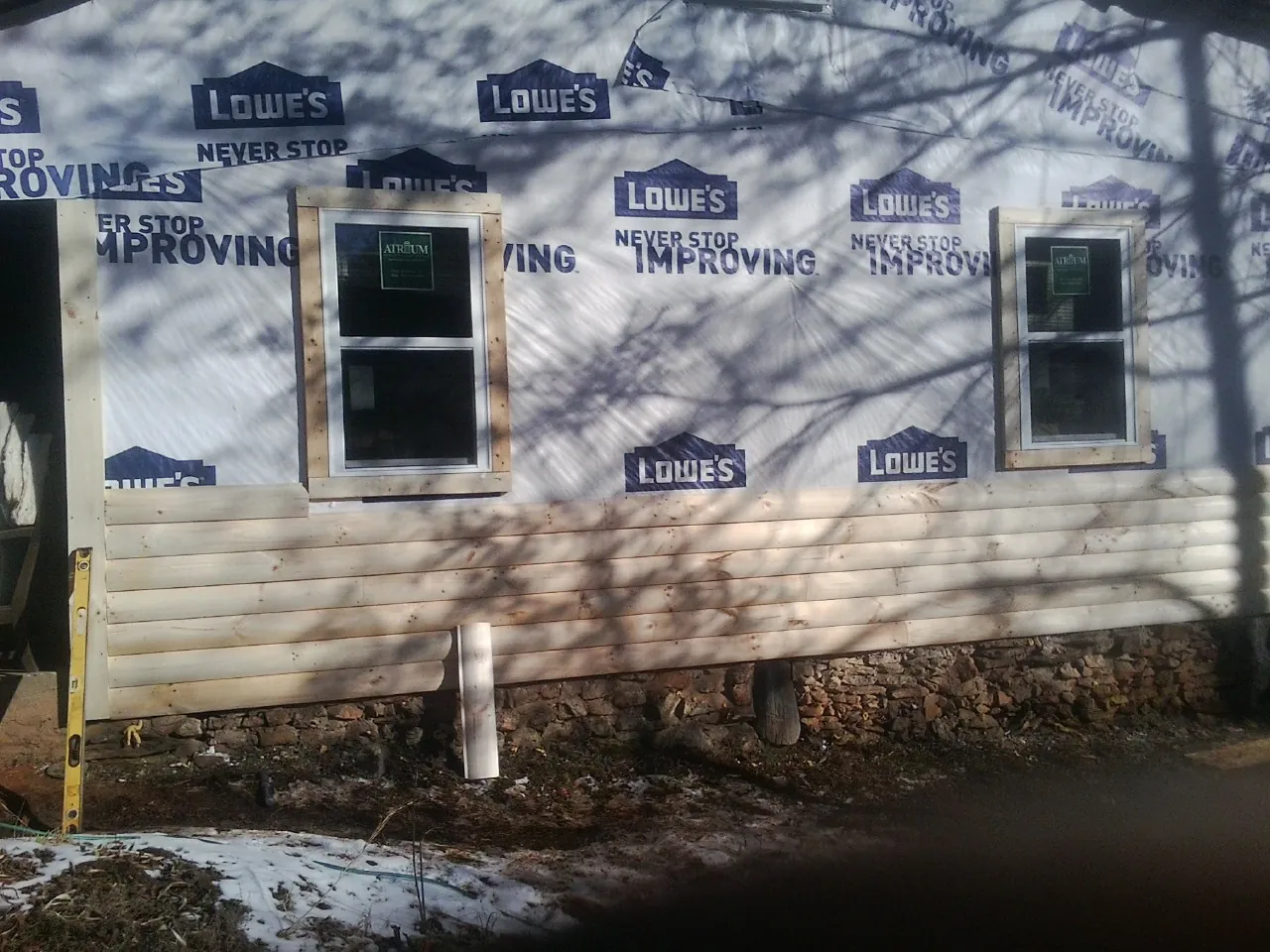 House wrap and new log siding going up on an exterior wall in Highland Mills