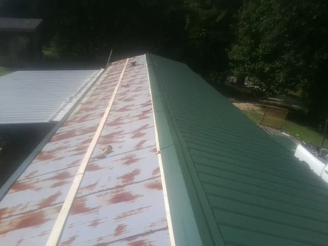 Old rusted panels beside newly installed green metal roofing — Wind Damage Roof Repair by Roofing Brothers in Highland Mills