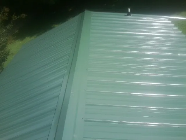 New green metal panels meeting at the ridge of a roof — Flat Roof Repair work by our crew in Highland Mills