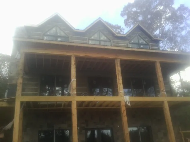 Dormers and porch framing on a large log home under construction — Roof Coating work by our crew in Highland Mills