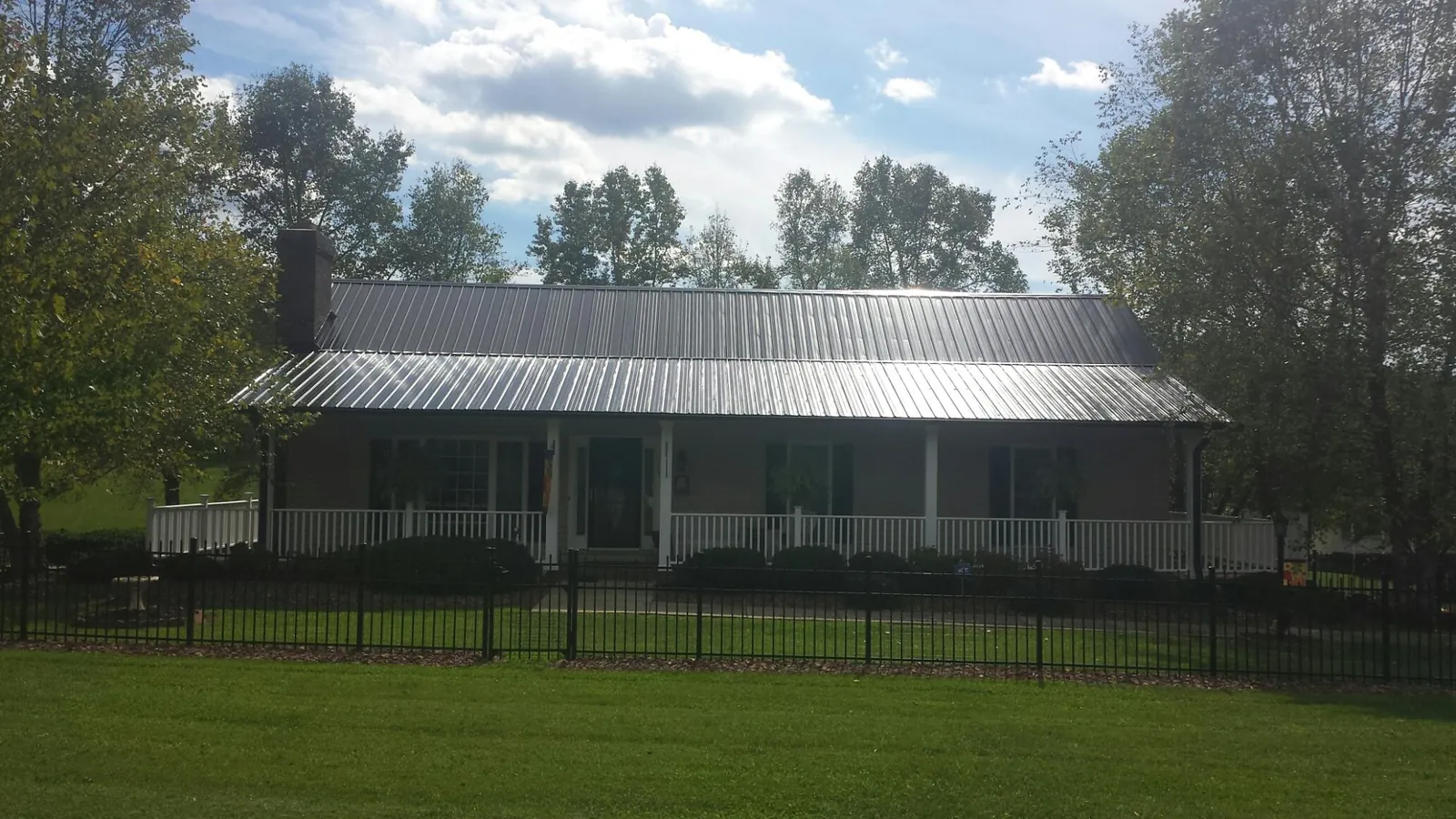 Gray metal roof on a brick ranch with a full width front porch — Gutter Guard Installation work by our crew in Highland Mills