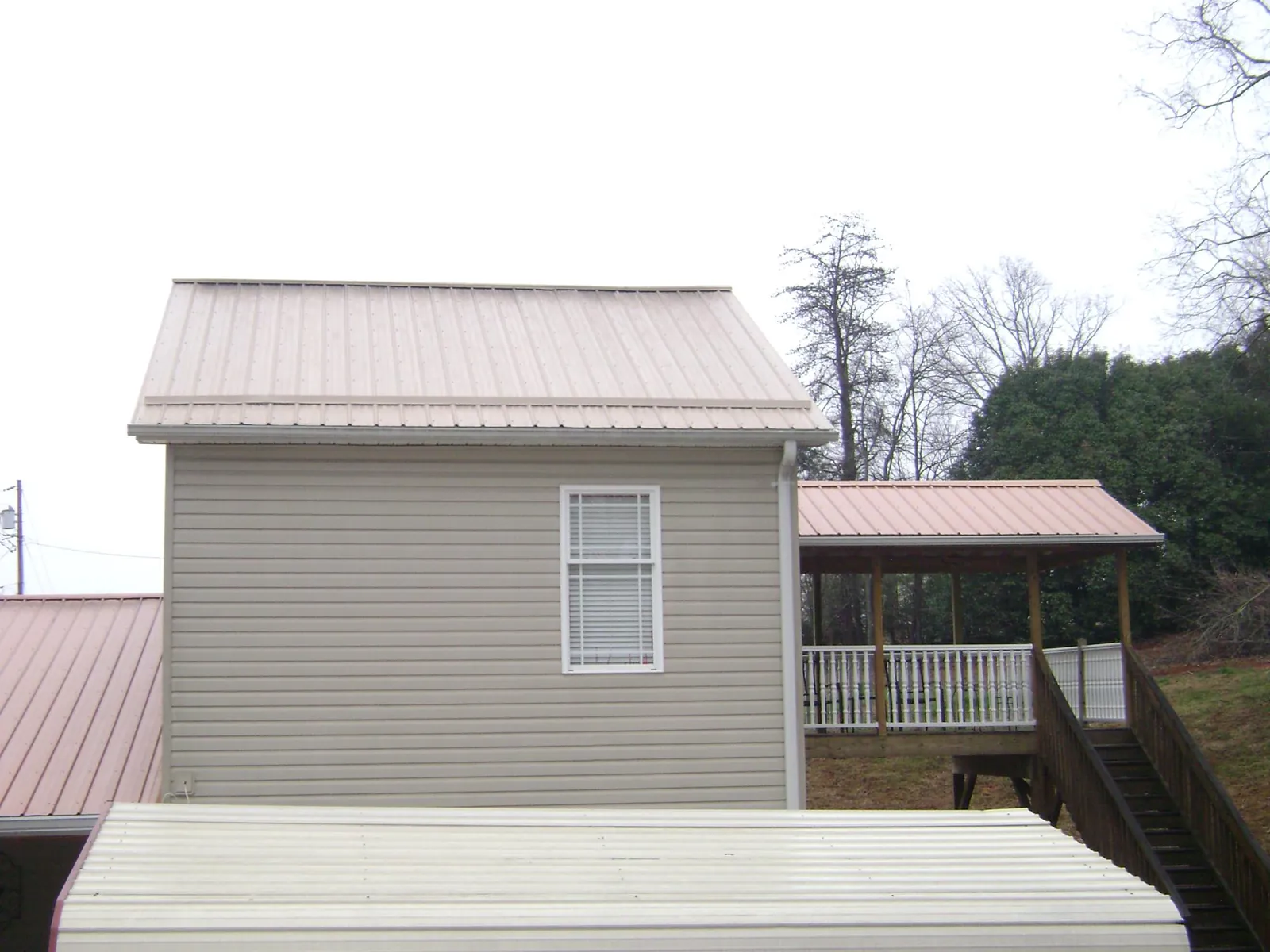Tan metal roofs on a two story addition and attached porch, from a Roof Replacement job in Highland Mills