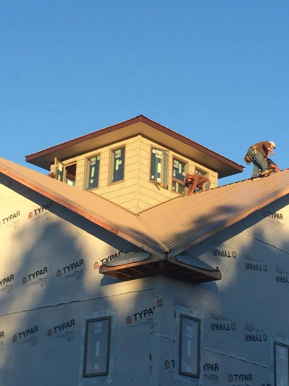 Roofers working around a rooftop cupola on a new metal roof at sunset — Roof Waterproofing in Highland Mills by Roofing Brothers